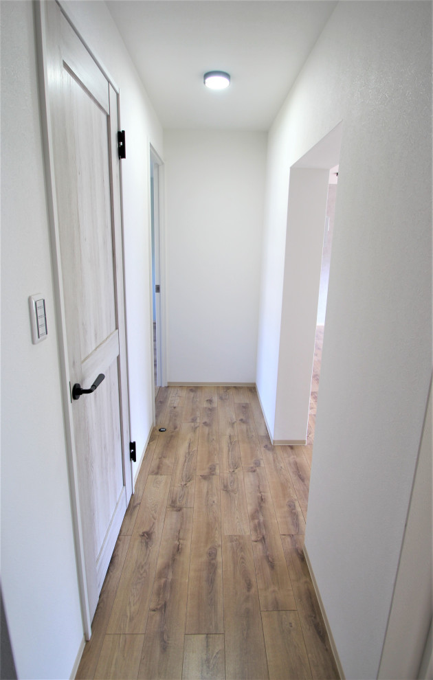 Immagine di un ingresso o corridoio stile rurale con pareti bianche, pavimento in compensato, pavimento marrone, soffitto in carta da parati e carta da parati