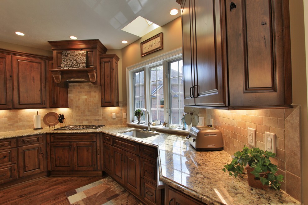 Example of a mid-sized medium tone wood floor eat-in kitchen design with an undermount sink, medium tone wood cabinets, quartzite countertops, beige backsplash, ceramic backsplash, stainless steel appliances and an island