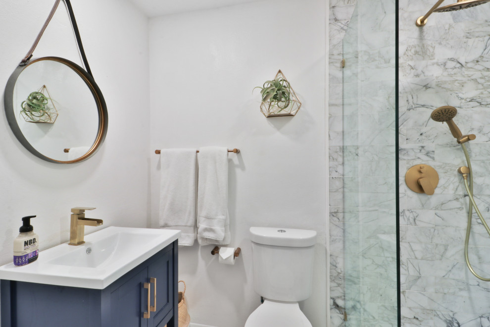 Mid-sized transitional master bathroom in Los Angeles with shaker cabinets, blue cabinets, an alcove shower, a two-piece toilet, gray tile, subway tile, grey walls, dark hardwood floors, an undermount sink, marble benchtops, brown floor, a sliding shower screen, grey benchtops, an enclosed toilet, a double vanity and a freestanding vanity.