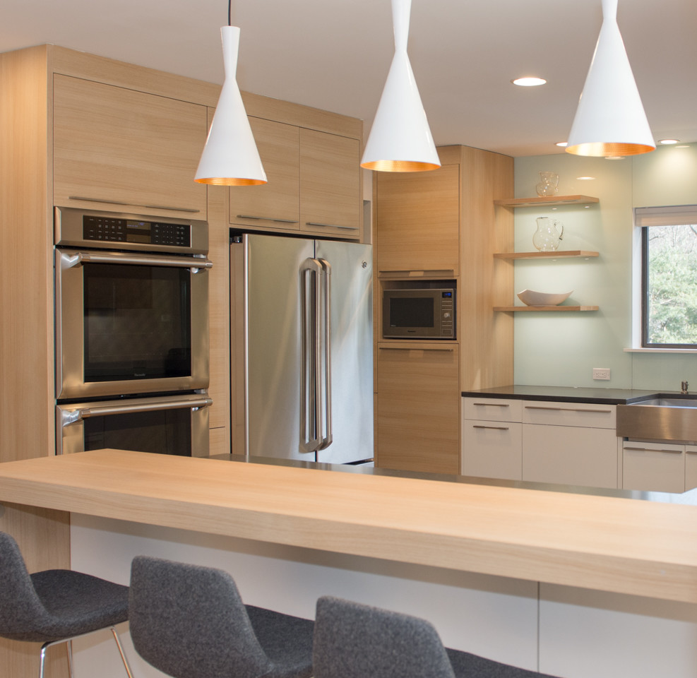 Design ideas for a mid-sized modern u-shaped eat-in kitchen in New York with an undermount sink, flat-panel cabinets, light wood cabinets, solid surface benchtops, blue splashback, glass sheet splashback, stainless steel appliances, medium hardwood floors and a peninsula.
