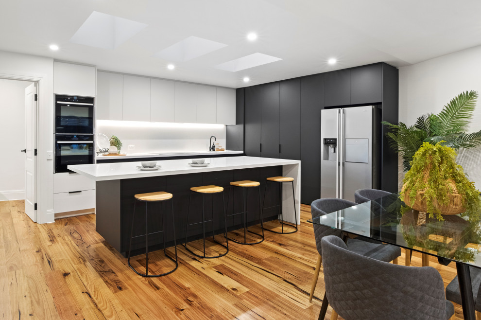 Design ideas for a mid-sized contemporary l-shaped eat-in kitchen in Melbourne with flat-panel cabinets, quartz benchtops, with island and white benchtop.