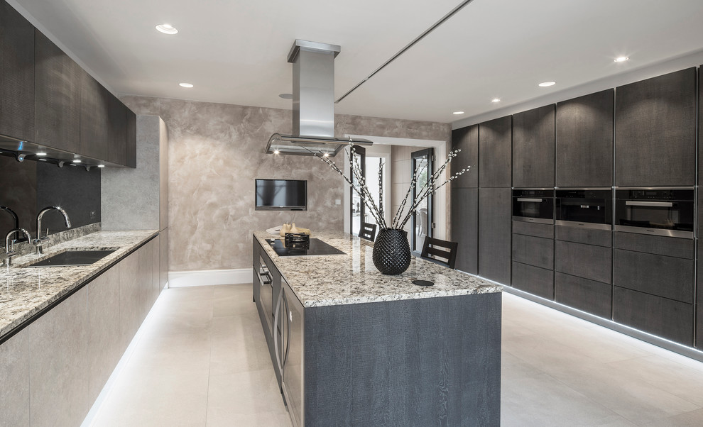 Photo of a contemporary galley kitchen in London with an undermount sink, flat-panel cabinets, grey cabinets, black splashback and with island.