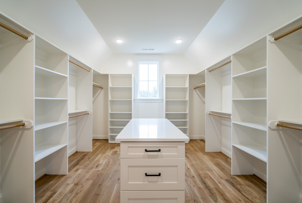 This is an example of a large country gender-neutral walk-in wardrobe in Raleigh with medium hardwood floors and brown floor.