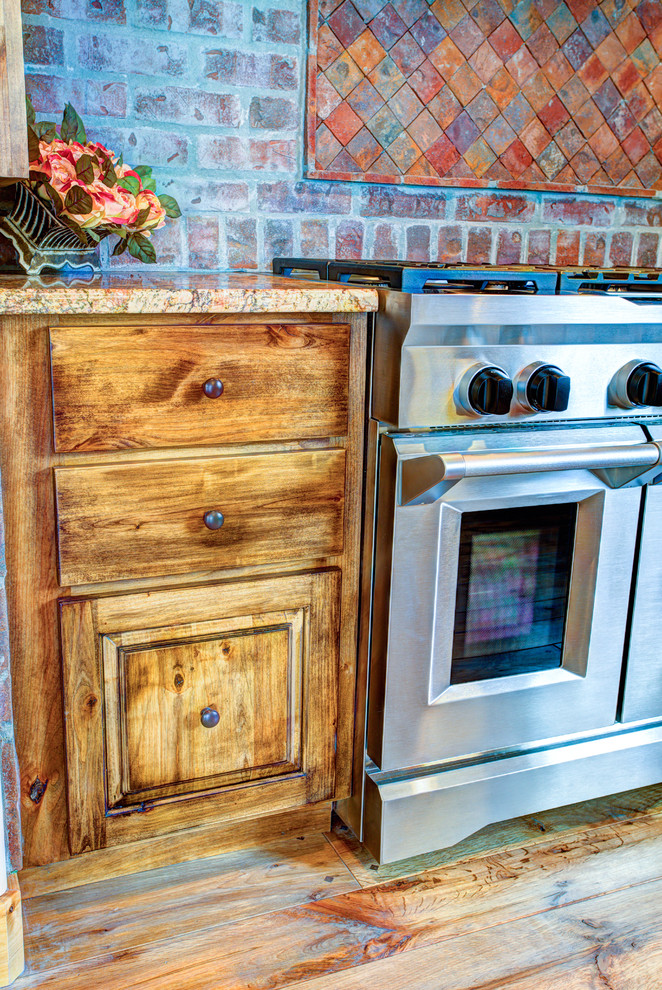 Example of a large mountain style u-shaped medium tone wood floor kitchen pantry design with a drop-in sink, glass-front cabinets, medium tone wood cabinets, beige backsplash, stainless steel appliances and an island