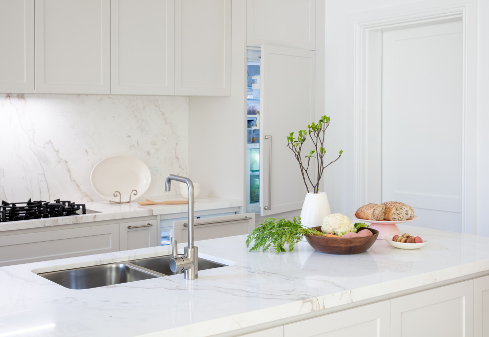 Aménagement d'une cuisine américaine linéaire contemporaine de taille moyenne avec un évier 2 bacs, un placard à porte shaker, des portes de placard beiges, plan de travail en marbre, une crédence beige, une crédence en dalle de pierre, un électroménager en acier inoxydable, un sol en bois brun, îlot et un plan de travail beige.