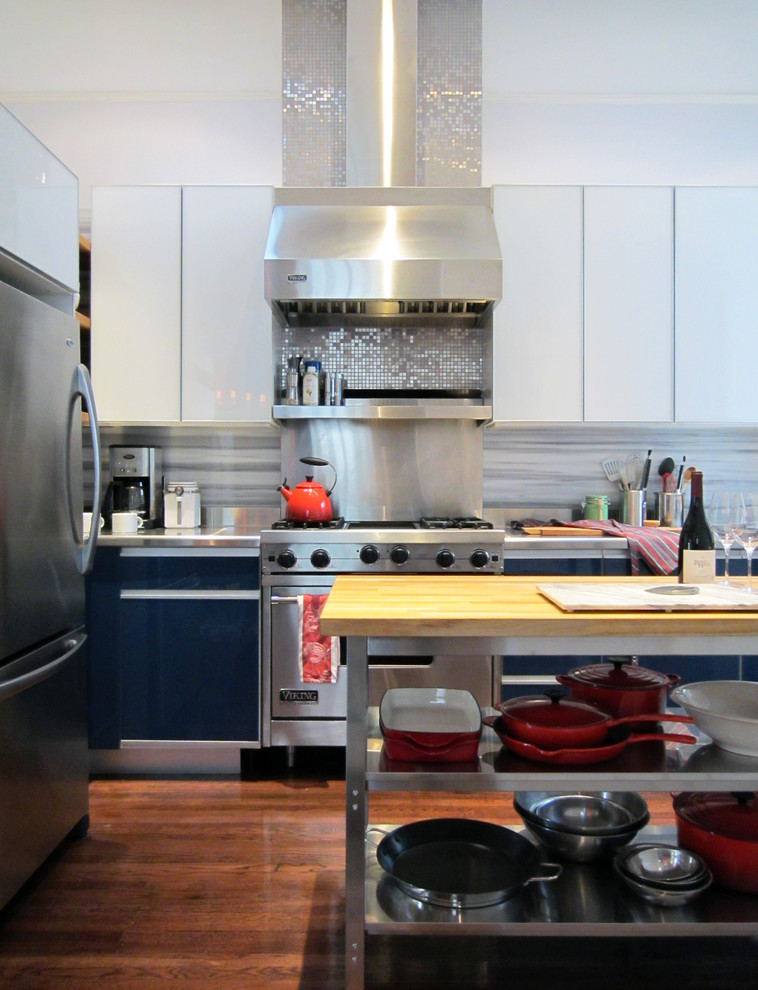 This is an example of a contemporary kitchen in San Francisco with stainless steel appliances, flat-panel cabinets, white cabinets, stainless steel benchtops, white splashback and marble splashback.