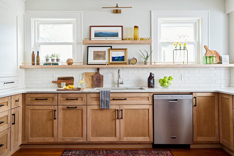 他の地域にある高級な広いトランジショナルスタイルのおしゃれなアイランドキッチン (淡色木目調キャビネット、白いキッチンパネル、シルバーの調理設備、茶色い床、白いキッチンカウンター) の写真