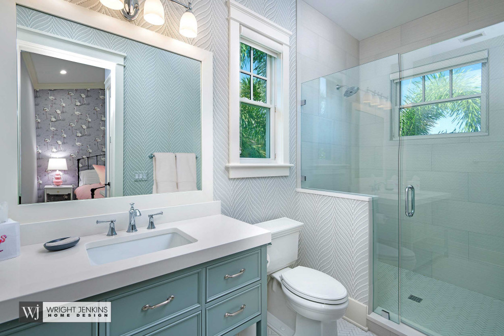 Mid-sized beach style 3/4 bathroom in Tampa with beaded inset cabinets, blue cabinets, an alcove shower, a two-piece toilet, beige tile, travertine, beige walls, ceramic floors, an undermount sink, engineered quartz benchtops, white floor, a hinged shower door and white benchtops.
