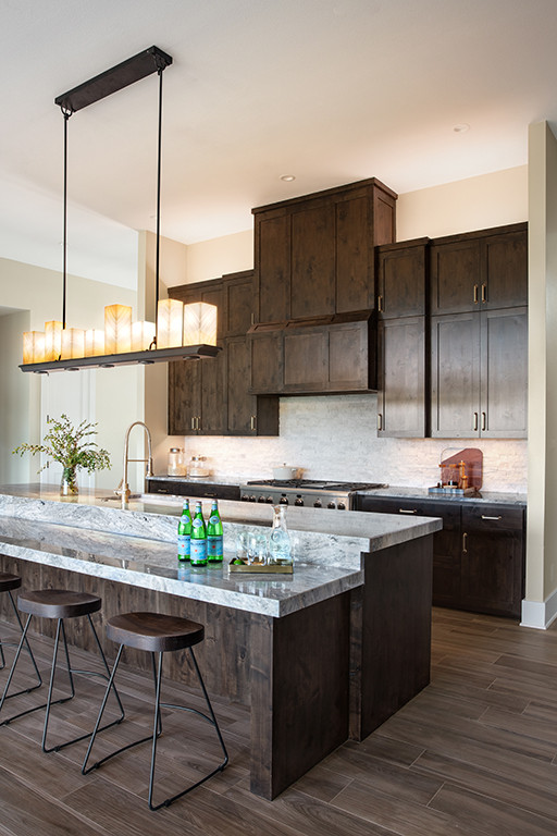Open concept kitchen - large transitional l-shaped dark wood floor and brown floor open concept kitchen idea in Austin with an undermount sink, shaker cabinets, dark wood cabinets, quartzite countertops, gray backsplash, stone tile backsplash, stainless steel appliances, an island and gray countertops