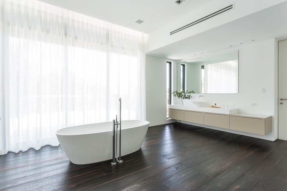 Photo of a contemporary master bathroom in Miami with a vessel sink, flat-panel cabinets, beige cabinets, a freestanding tub, an open shower, a wall-mount toilet, white walls and dark hardwood floors.
