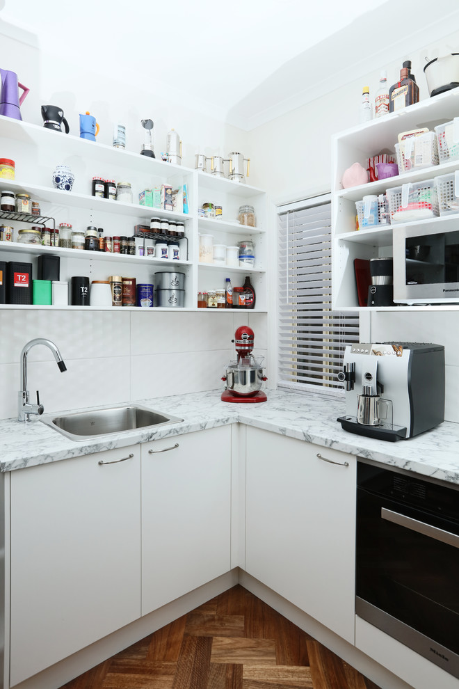 Design ideas for a mid-sized transitional galley kitchen pantry in Melbourne with with island, a drop-in sink, flat-panel cabinets, white cabinets, laminate benchtops, stainless steel appliances and dark hardwood floors.