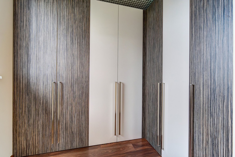 Modelo de armario vestidor unisex nórdico de tamaño medio con armarios con paneles lisos, puertas de armario blancas, suelo de madera en tonos medios y suelo marrón