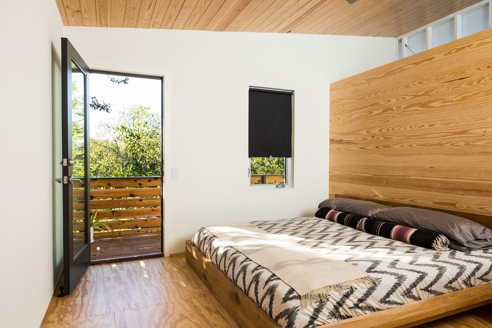 Photo of a mid-sized contemporary master bedroom in Austin with white walls, plywood floors and brown floor.