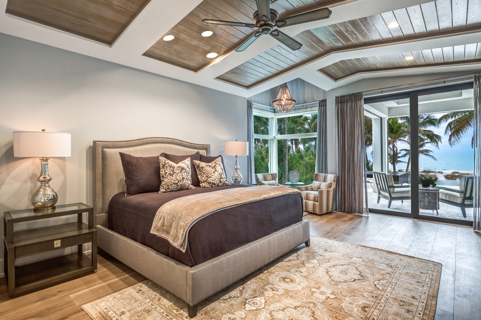 Beach style master bedroom in Other with grey walls and light hardwood floors.