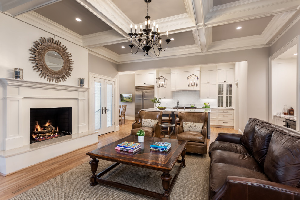 This is an example of a large traditional open concept family room in Other with a home bar, white walls, medium hardwood floors, a standard fireplace and a wood fireplace surround.
