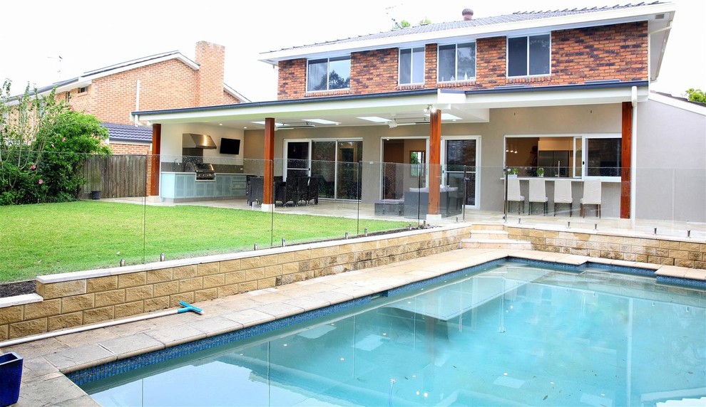 This is an example of a large contemporary backyard pool in Sydney with natural stone pavers.