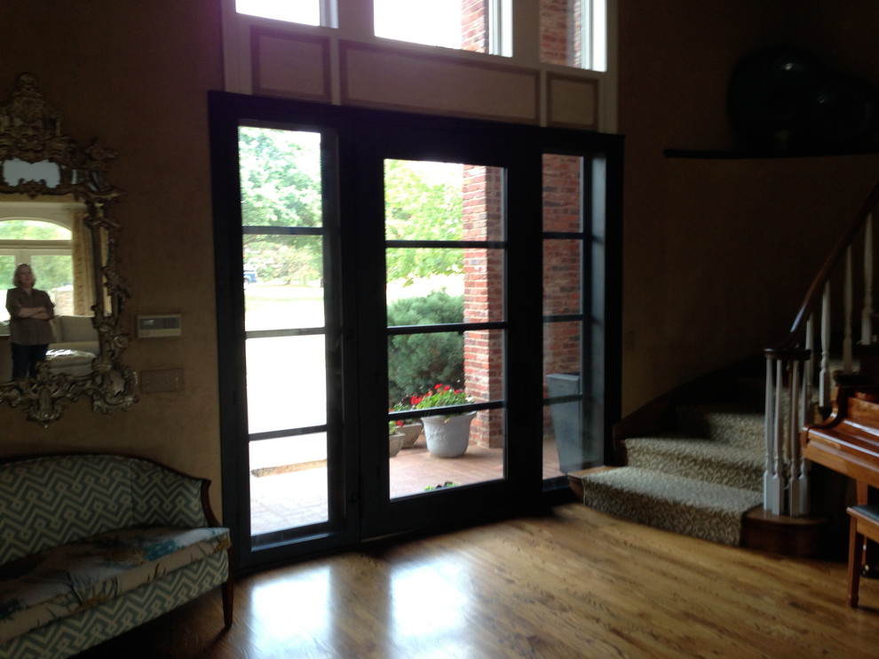 This is an example of a mid-sized traditional front door in Oklahoma City with beige walls, brick floors, a double front door and a glass front door.