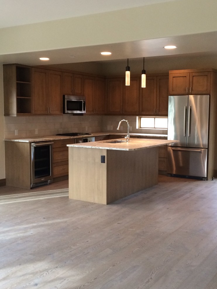 Example of a small transitional l-shaped medium tone wood floor kitchen design with an undermount sink, shaker cabinets, medium tone wood cabinets, granite countertops, beige backsplash, porcelain backsplash, stainless steel appliances and an island