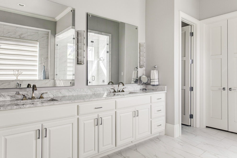 Photo of a large transitional master bathroom in Dallas with raised-panel cabinets, turquoise cabinets, a freestanding tub, a corner shower, a two-piece toilet, gray tile, marble, grey walls, marble floors, an undermount sink, marble benchtops, grey floor and a hinged shower door.