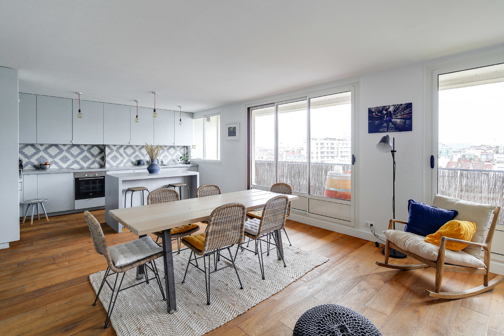 Aménagement d'une grande salle à manger ouverte sur la cuisine contemporaine avec un mur blanc, un sol en bois brun, aucune cheminée, un sol marron et éclairage.