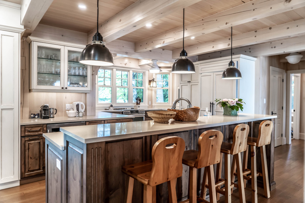 This is an example of a mid-sized country u-shaped eat-in kitchen in Other with an undermount sink, raised-panel cabinets, distressed cabinets, quartz benchtops, beige splashback, timber splashback, stainless steel appliances, light hardwood floors, with island, beige floor and beige benchtop.