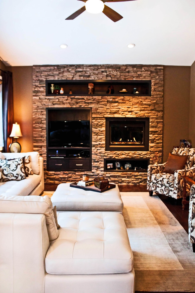 Photo of a traditional living room in Calgary with a built-in media wall, brown walls, dark hardwood floors, a standard fireplace and a stone fireplace surround.