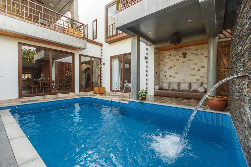 Asian courtyard custom-shaped pool in Bengaluru with concrete pavers.