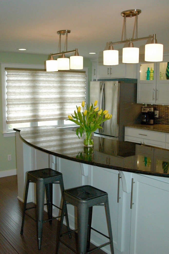 Enclosed kitchen - mid-sized transitional l-shaped medium tone wood floor and brown floor enclosed kitchen idea in Boston with an undermount sink, recessed-panel cabinets, white cabinets, granite countertops, multicolored backsplash, glass tile backsplash, stainless steel appliances and an island