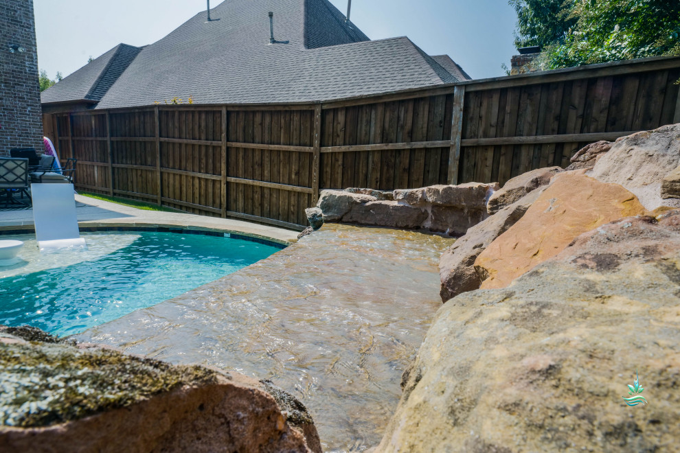 Mid-sized backyard custom-shaped natural pool in Dallas with with privacy feature and stamped concrete.