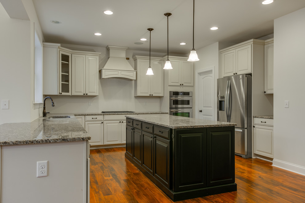Photo of a large transitional u-shaped open plan kitchen in Baltimore with an undermount sink, raised-panel cabinets, white cabinets, granite benchtops, white splashback, stainless steel appliances, bamboo floors and with island.