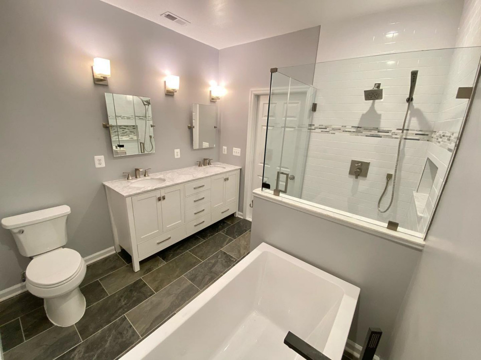Пример оригинального дизайна: главная ванная комната среднего размера в современном стиле с фасадами в стиле шейкер, белыми фасадами, отдельно стоящей ванной, открытым душем, раздельным унитазом, белой плиткой, плиткой кабанчик, серыми стенами, полом из сланца, врезной раковиной, мраморной столешницей, черным полом, душем с распашными дверями, серой столешницей, нишей, тумбой под две раковины и напольной тумбой