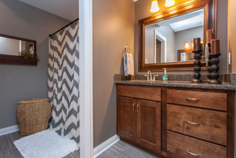 Mid-sized transitional kids' gray tile and ceramic tile ceramic tile alcove bathtub photo with an undermount sink, beaded inset cabinets, medium tone wood cabinets, granite countertops, a two-piece toilet and gray walls