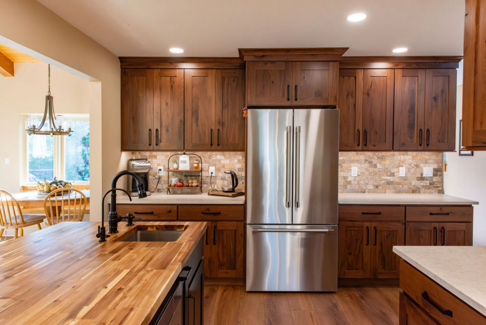 Inspiration for a large rustic dark wood floor and brown floor eat-in kitchen remodel in Denver with recessed-panel cabinets, dark wood cabinets, wood countertops, travertine backsplash, stainless steel appliances, brown countertops, a farmhouse sink, an island and multicolored backsplash