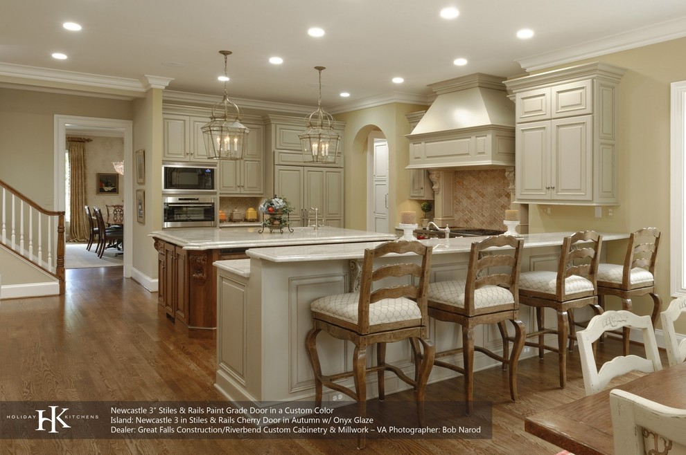 Inspiration for a large transitional u-shaped eat-in kitchen in New York with an undermount sink, raised-panel cabinets, white cabinets, marble benchtops, beige splashback, stone tile splashback, stainless steel appliances, dark hardwood floors and with island.