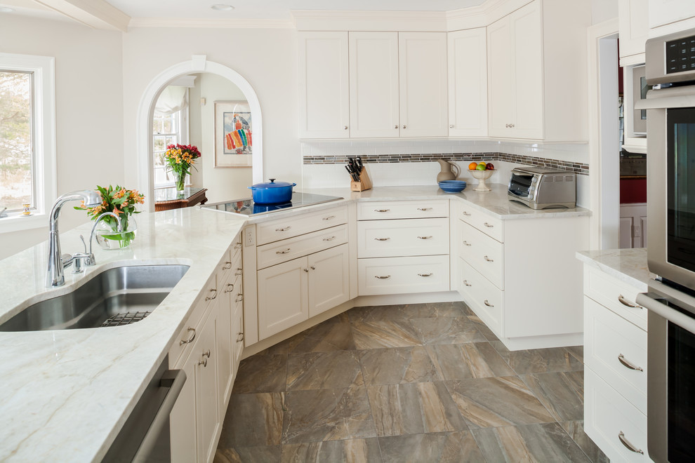 Design ideas for a mid-sized traditional l-shaped eat-in kitchen in New York with an undermount sink, shaker cabinets, white cabinets, white splashback, stainless steel appliances, no island, marble benchtops, subway tile splashback and ceramic floors.