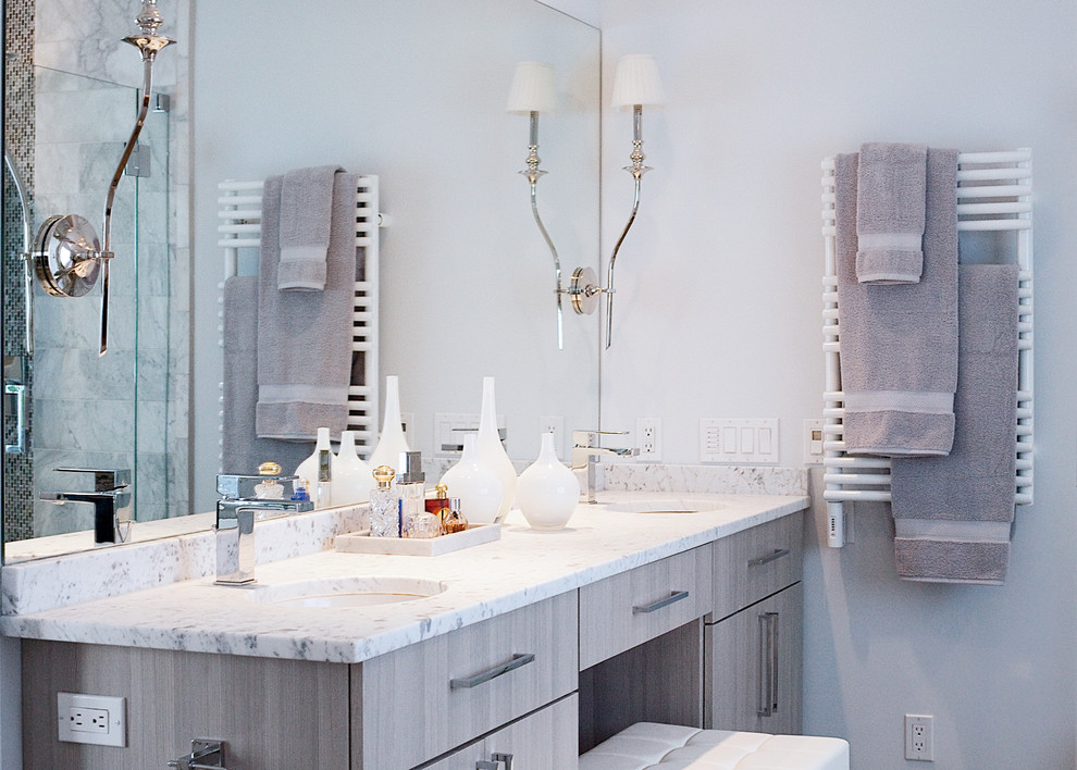 Photo of a mid-sized contemporary master bathroom in New York with an undermount sink, flat-panel cabinets, grey cabinets, marble benchtops, a freestanding tub, a corner shower, a two-piece toilet, gray tile, grey walls and porcelain floors.