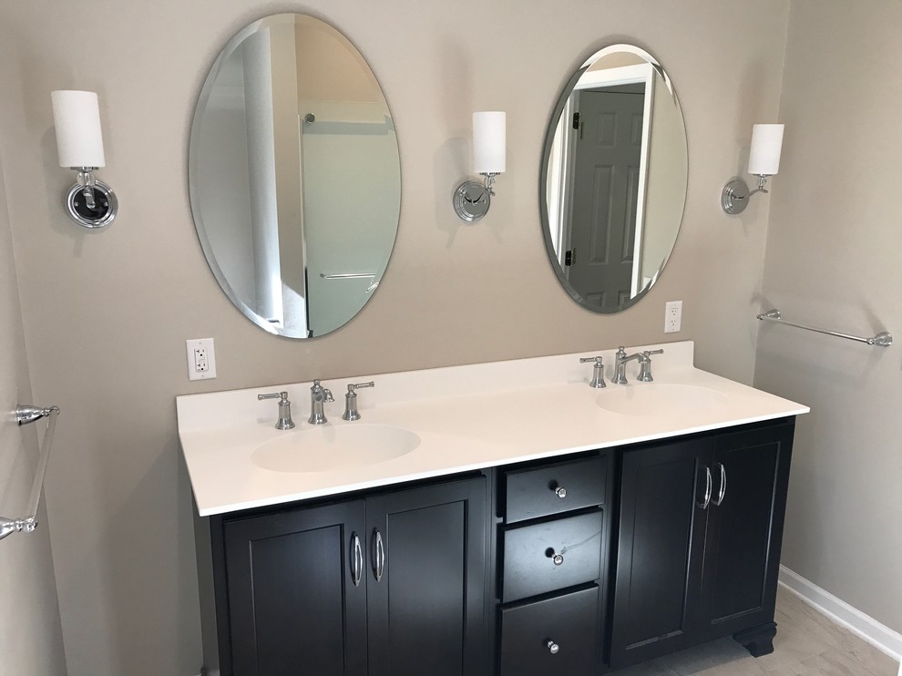 Inspiration for a mid-sized transitional ceramic tile and multicolored floor bathroom remodel with recessed-panel cabinets, brown cabinets, beige walls, an integrated sink, solid surface countertops and white countertops