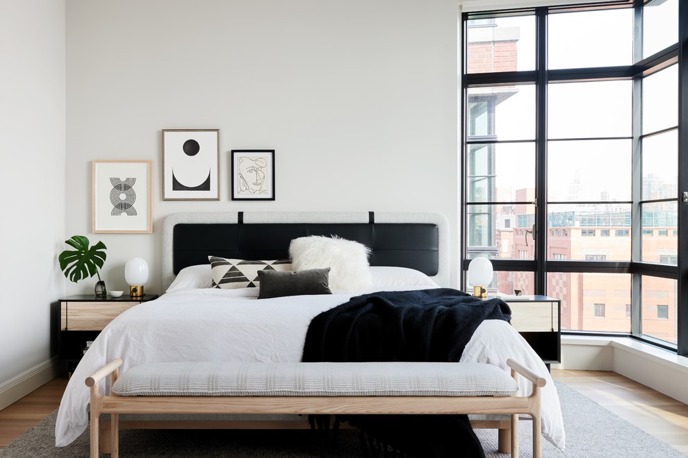 This is an example of a scandinavian master bedroom in New York with white walls, light hardwood floors and no fireplace.