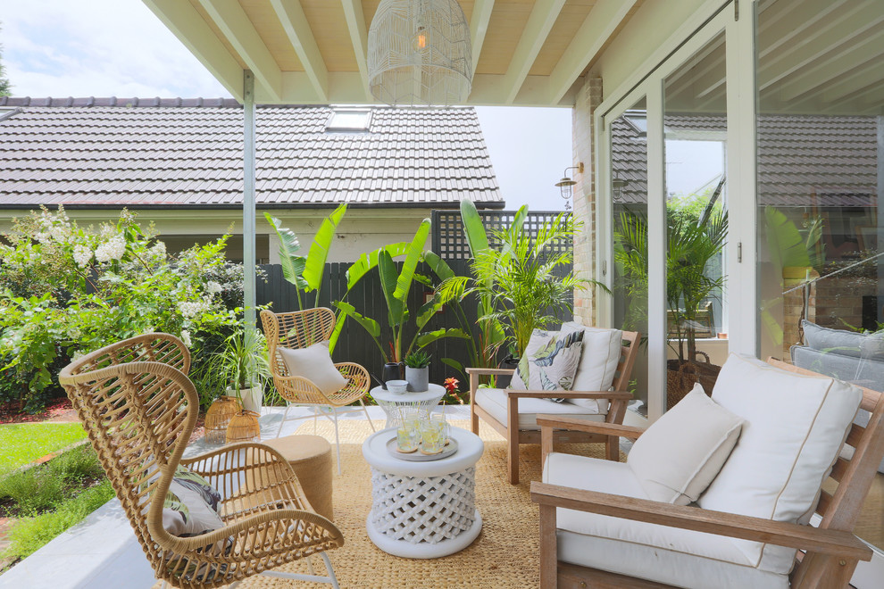 Photo of a small beach style backyard patio in Sydney with tile and a roof extension.