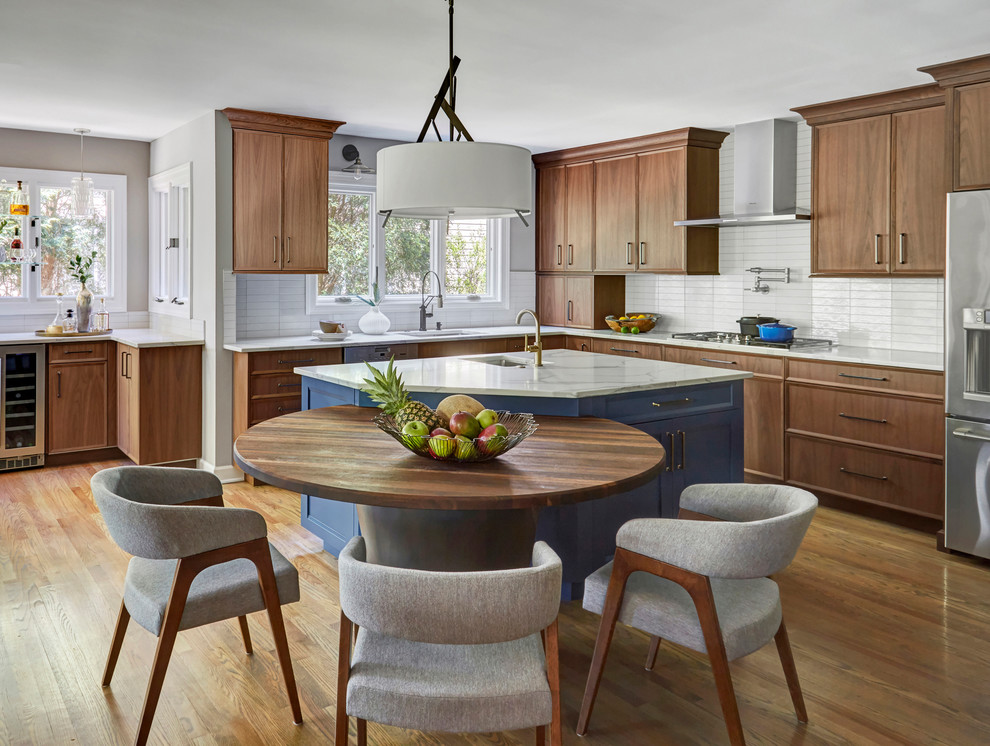 This is an example of a large modern l-shaped open plan kitchen in Chicago with an undermount sink, flat-panel cabinets, medium wood cabinets, quartz benchtops, white splashback, subway tile splashback, stainless steel appliances, medium hardwood floors, with island, brown floor and white benchtop.