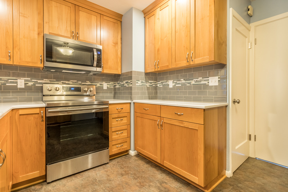 Mid-sized transitional u-shaped vinyl floor and brown floor enclosed kitchen photo with an undermount sink, shaker cabinets, gray cabinets, quartz countertops, gray backsplash, subway tile backsplash, stainless steel appliances, no island and white countertops