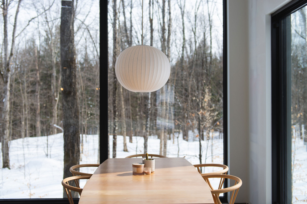 На фото: столовая в скандинавском стиле с белыми стенами, бетонным полом, печью-буржуйкой и сводчатым потолком