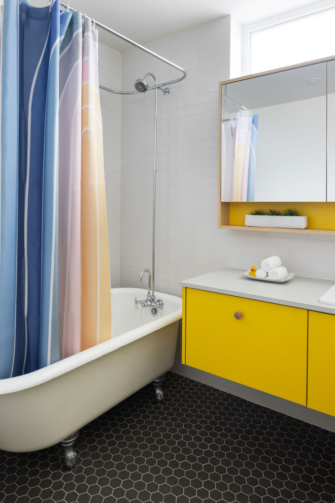 Пример оригинального дизайна: детская ванная комната среднего размера в современном стиле с плоскими фасадами, желтыми фасадами, ванной на ножках, душем над ванной, белой плиткой, плиткой кабанчик, белыми стенами, накладной раковиной, столешницей из ламината, черным полом, шторкой для ванной, белой столешницей, тумбой под одну раковину и подвесной тумбой