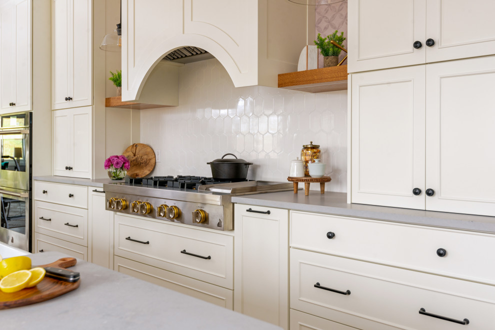 Example of a large medium tone wood floor and exposed beam eat-in kitchen design with white backsplash, stainless steel appliances and an island