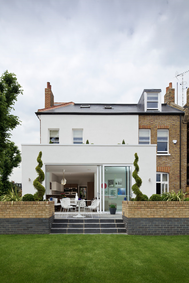 Inspiration for a contemporary split-level white exterior in London with mixed siding and a gable roof.