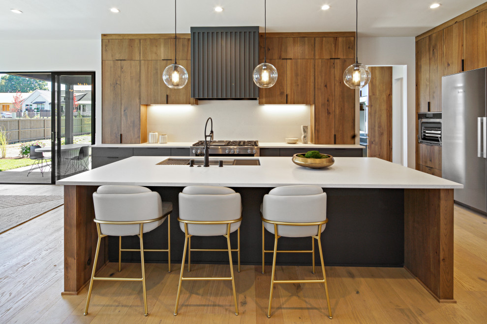 Eat-in kitchen - large contemporary single-wall medium tone wood floor and brown floor eat-in kitchen idea in Portland with a drop-in sink, flat-panel cabinets, medium tone wood cabinets, granite countertops, beige backsplash, stainless steel appliances, an island and beige countertops