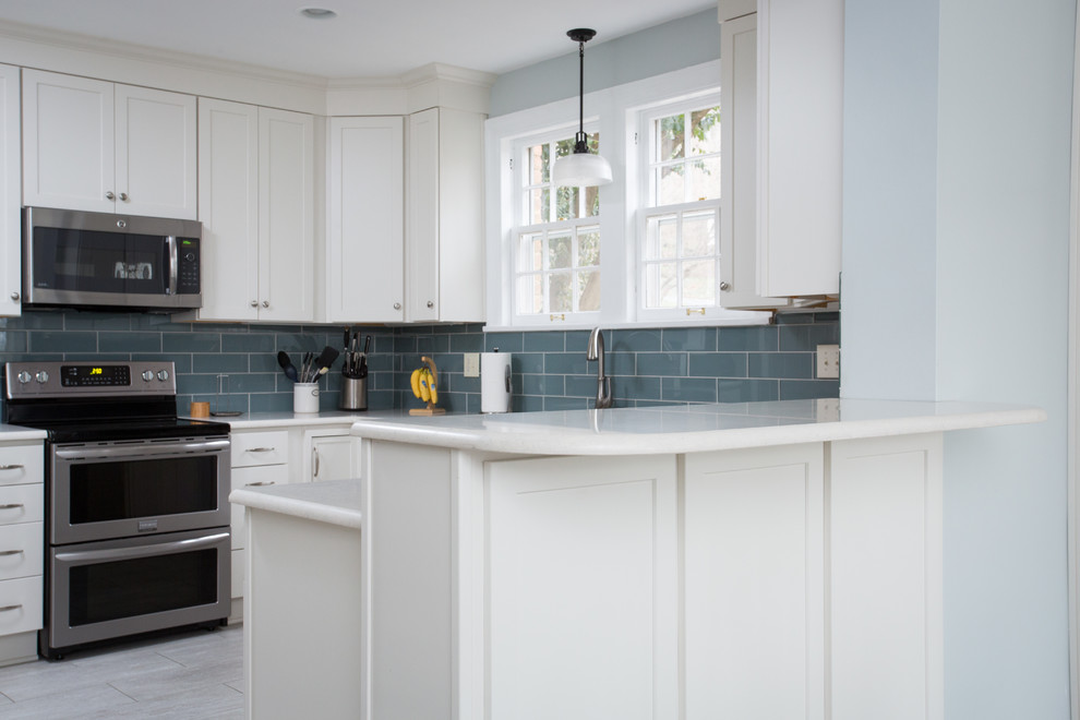 Eat-in kitchen - mid-sized transitional u-shaped vinyl floor eat-in kitchen idea with an undermount sink, shaker cabinets, white cabinets, quartz countertops, blue backsplash, glass tile backsplash, stainless steel appliances and a peninsula