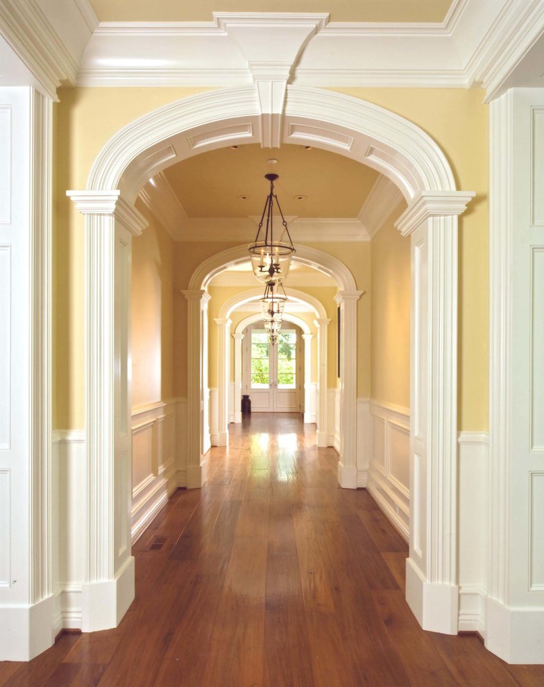 Photo of an expansive traditional hallway with yellow walls and medium hardwood floors.
