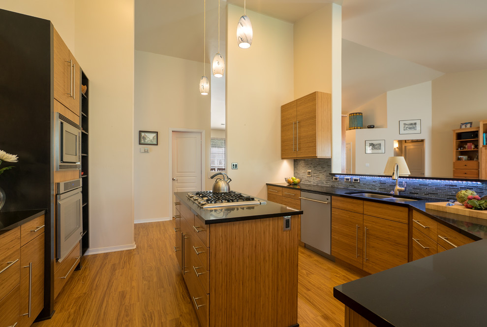 Mid-sized contemporary kitchen in Phoenix with an undermount sink, flat-panel cabinets, medium wood cabinets, granite benchtops, blue splashback, matchstick tile splashback, stainless steel appliances, medium hardwood floors, with island and brown floor.