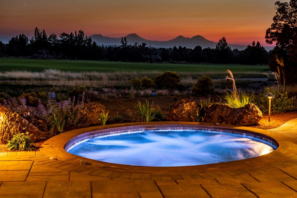 Example of a large mountain style backyard stone pool design with a fireplace and a roof extension
